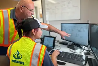 photo of two Marmer Construction employees working together at a desktop computer